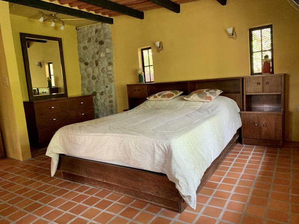 La cama matrimonial con mesas de noche y cómoda de madera