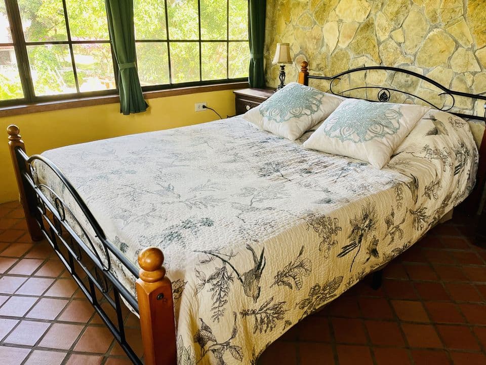 La cama matrimonial junto a la pared de piedra